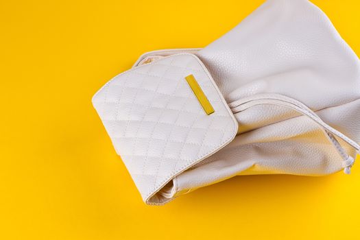 The female white leather backpack on a yellow background