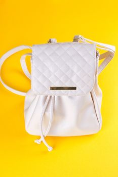 The female white leather backpack on a yellow background