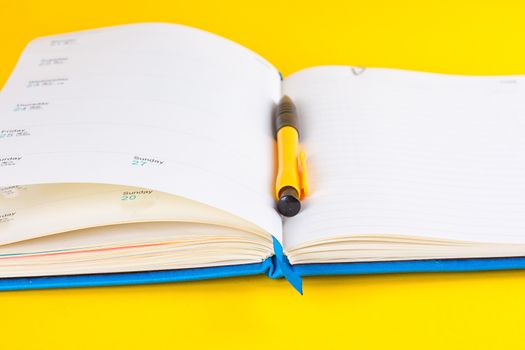 Open diary and pen on a yellow background