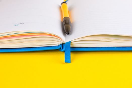 Open diary and pen on a yellow background