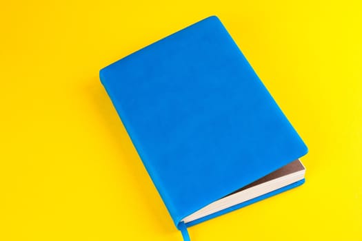 Blue closed diary on a yellow background