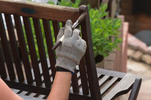 Painting and applying protective eco-friendly paint on a wooden garden chair.