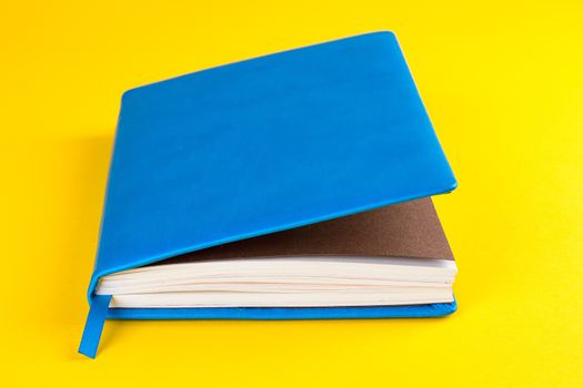 Blue closed diary on a yellow background