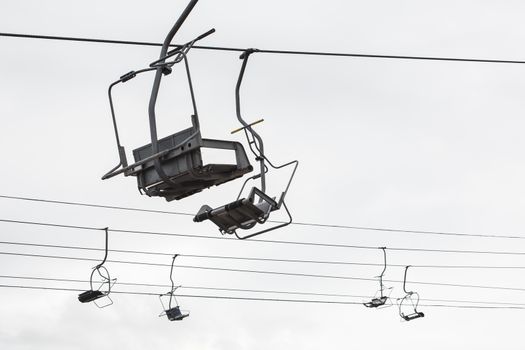 Empty chairlift with cloudy sky in the background. Cableway chairlift