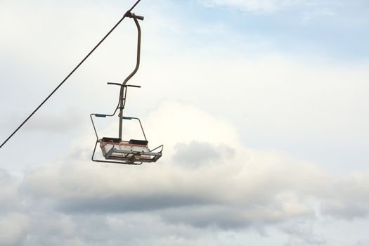 Empty chairlift with cloudy sky in the background. Cableway chairlift