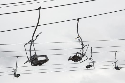 Empty chairlift with cloudy sky in the background. Cableway chairlift