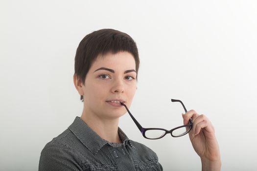 Young attractive girl in black and white plaid shirt seriously holding glasses near her mouth. Isolated on white background, mask included.