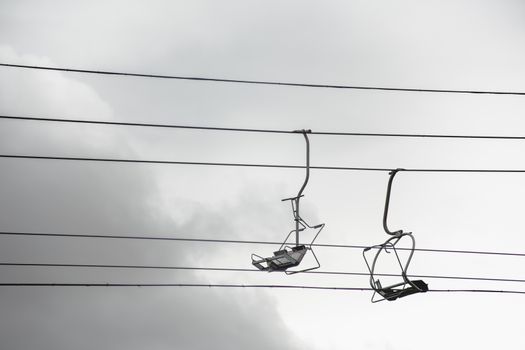 Empty chairlift with cloudy sky in the background. Cableway chairlift