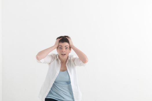 Headshot of hysterical Caucasian freckled student girl looking in despair and panic, being late for important exam or event, not knowing what to do, hands on her head, mouth wide open.