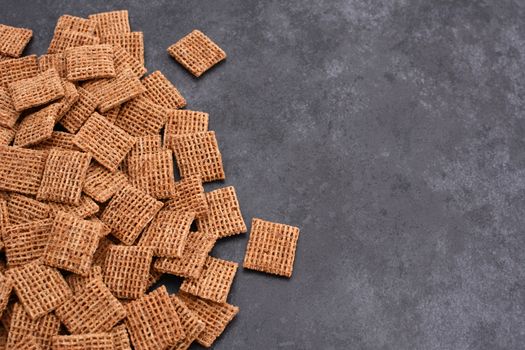Malted shredded wheat biscuits breakfast cereal in a border line with copy space on a dark grey slate tile background