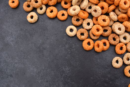 Multigrain hoops breakfast cereal diagonal border with copy space on a dark grey slate tile background