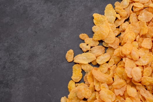 Corn flakes breakfast cereal in a diagonal line with copy space on a dark grey slate tile background