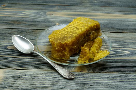 Honey with honeycomb in a glass plate on a wooden table
