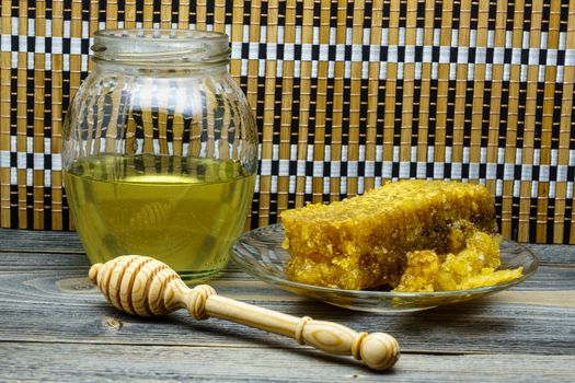 Honey with honeycomb in a glass plate on a wooden table