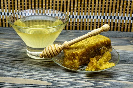 Honey with honeycomb in a glass plate on a wooden table