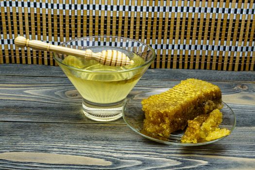 Honey with honeycomb in a glass plate on a wooden table