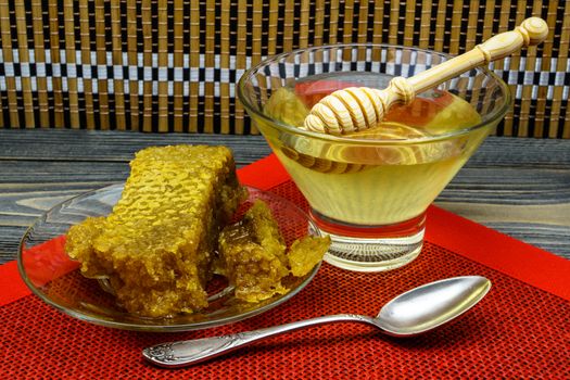 Honey with honeycomb in a glass plate on a wooden table