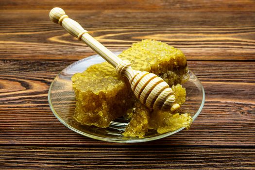 Honey with honeycomb in a glass plate on a wooden table