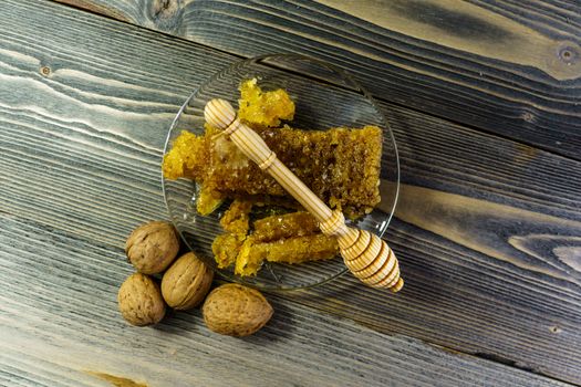 Honey with honeycomb in a glass plate on a wooden table