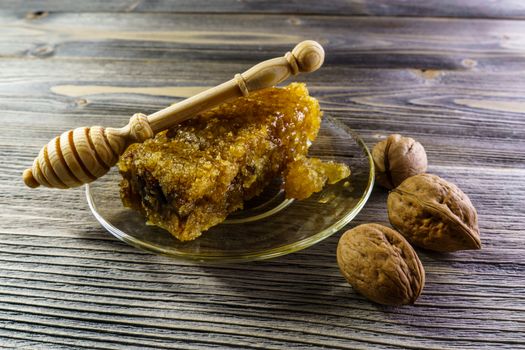 Honey with honeycomb in a glass plate on a wooden table