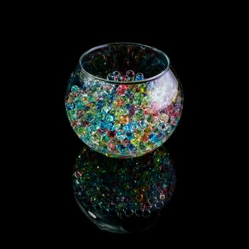 Colored hydrogel balls in a glass vase on a black background