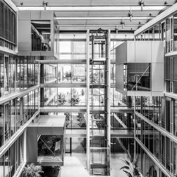 Main hall, staircase and windows of morden office building. Contemporary corporate business architecture. Munich Trading and Technology Centre. Black and white image.