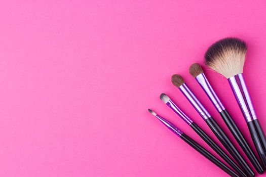 Set of makeup brushes on pink background. Top view point, flat lay.