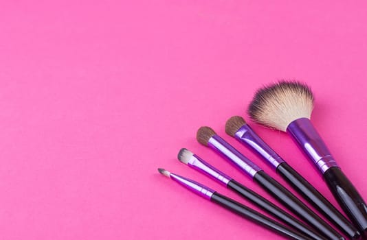 Set of makeup brushes on pink background. Top view point, flat lay.