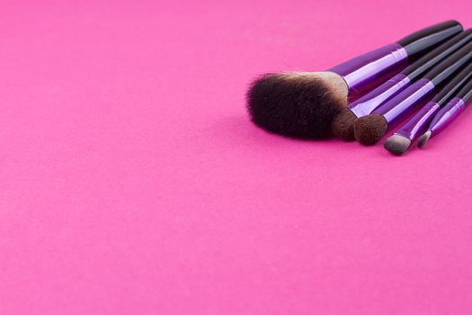 Set of makeup brushes on pink background. Top view point, flat lay.