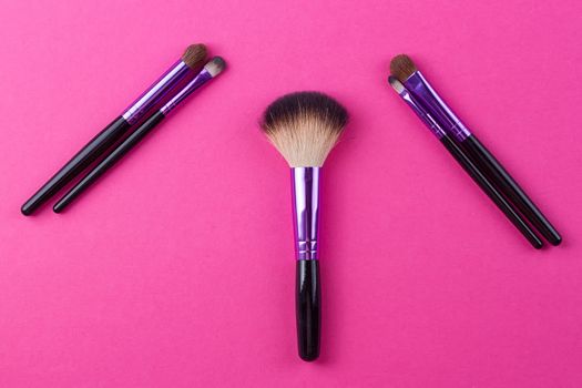 Set of makeup brushes on pink background. Top view point, flat lay.