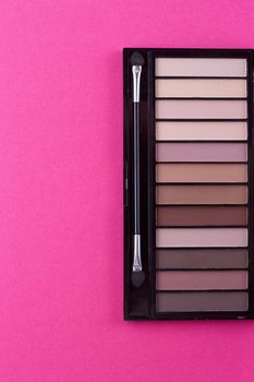 Set of nude eyeshadows in black case on pink background