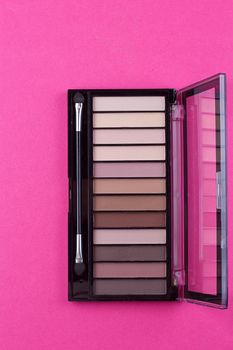 Set of nude eyeshadows in black case on pink background