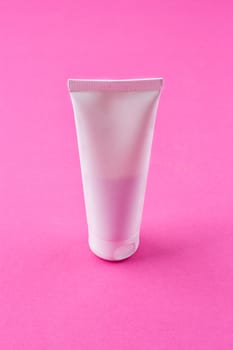 Blank pink cosmetic tube pack Of Cream Or Gel on the pink background