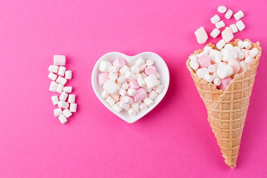 Love concept. Plate in the shape of heart with a marshmallow on a pink background. I love