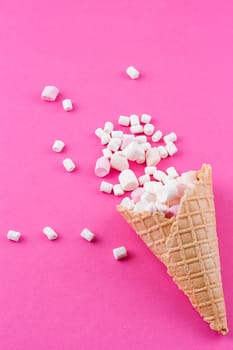 Marshmallows ice-cream and waffle cones on a pink background