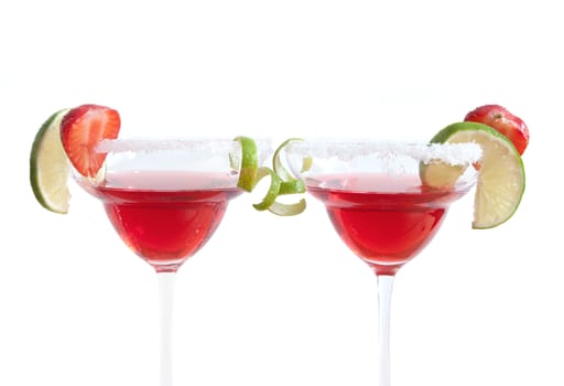 Two cocktail glasses with lime and strawberry slices over a white background