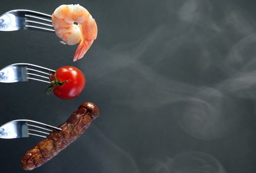 Barbecued ingredients including shrimp and sausage on forks with background space 