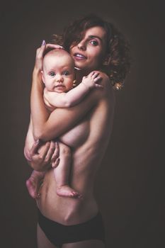 Young mother holding a baby in her arms. Studio shot