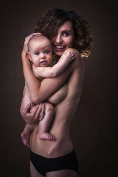 Young mother holding a baby in her arms. Studio shot