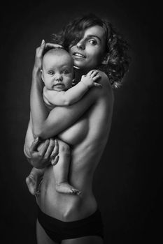 Young mother holding a baby in her arms. Studio shot