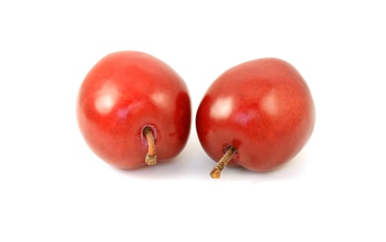 Two ripe red plums with stalks, isolated on a white background