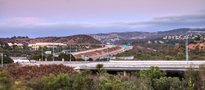 Highway in Irvine, California, at sunset with mountain range in the distance in summer
