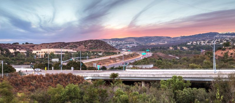 Highway in Irvine, California, at sunset with mountain range in the distance in summer
