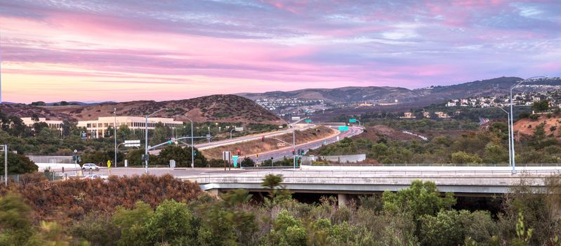 Highway in Irvine, California, at sunset with mountain range in the distance in summer