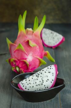 Ripe Dragon fruit  with slice in bowl over wooden background , still life