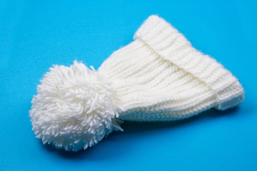 White winter knitted cap on blue background