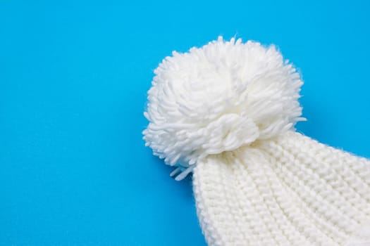 White winter knitted cap on blue background