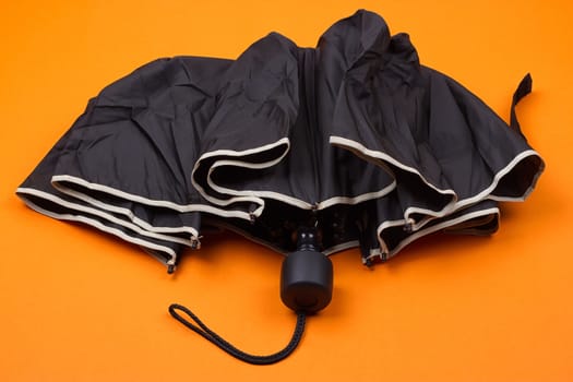 closed black umbrella on the orange background