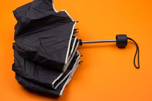 closed black umbrella on the orange background