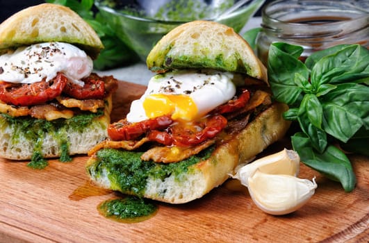 Toasted ciabatta with pesto, slices of bacon, sun-dried tomatoes and poached egg